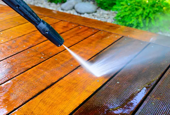 Close up of hose power washing a dirty deck.